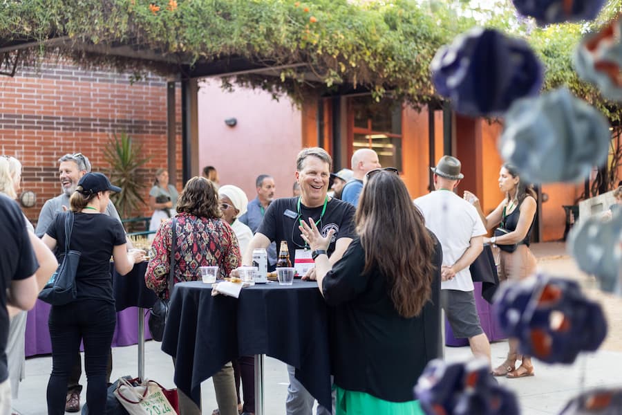 Conference attendees mingle and network outdoors around high tables at an AME Institute social gathering in Burbank.